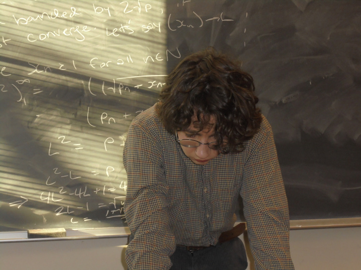 A portrait of Andrew by a chalkboard.